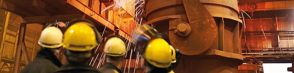 робітники слідкують за роботою важкого обладнання на металообробному заводі
