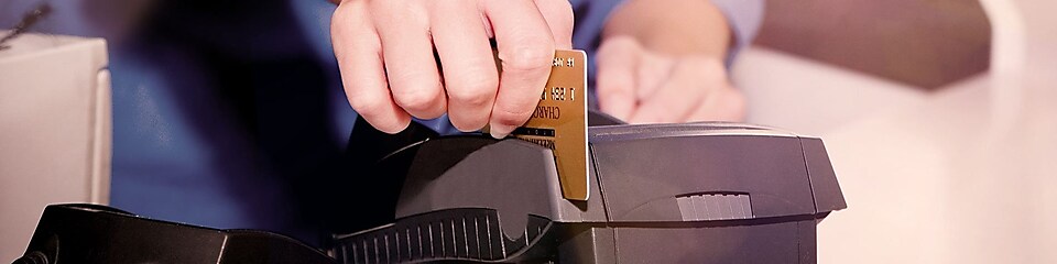 Людина проводить кредитною картою через термінал